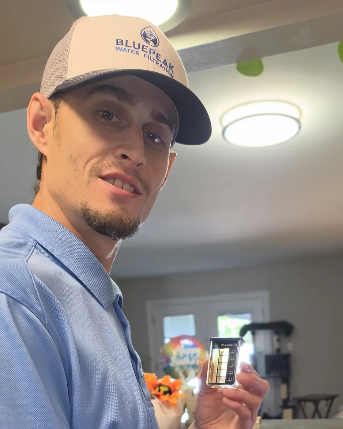 Branden, el dueño de BluePeak Water Filtration, con un vial de prueba de agua en el fregadero de una cocina.
