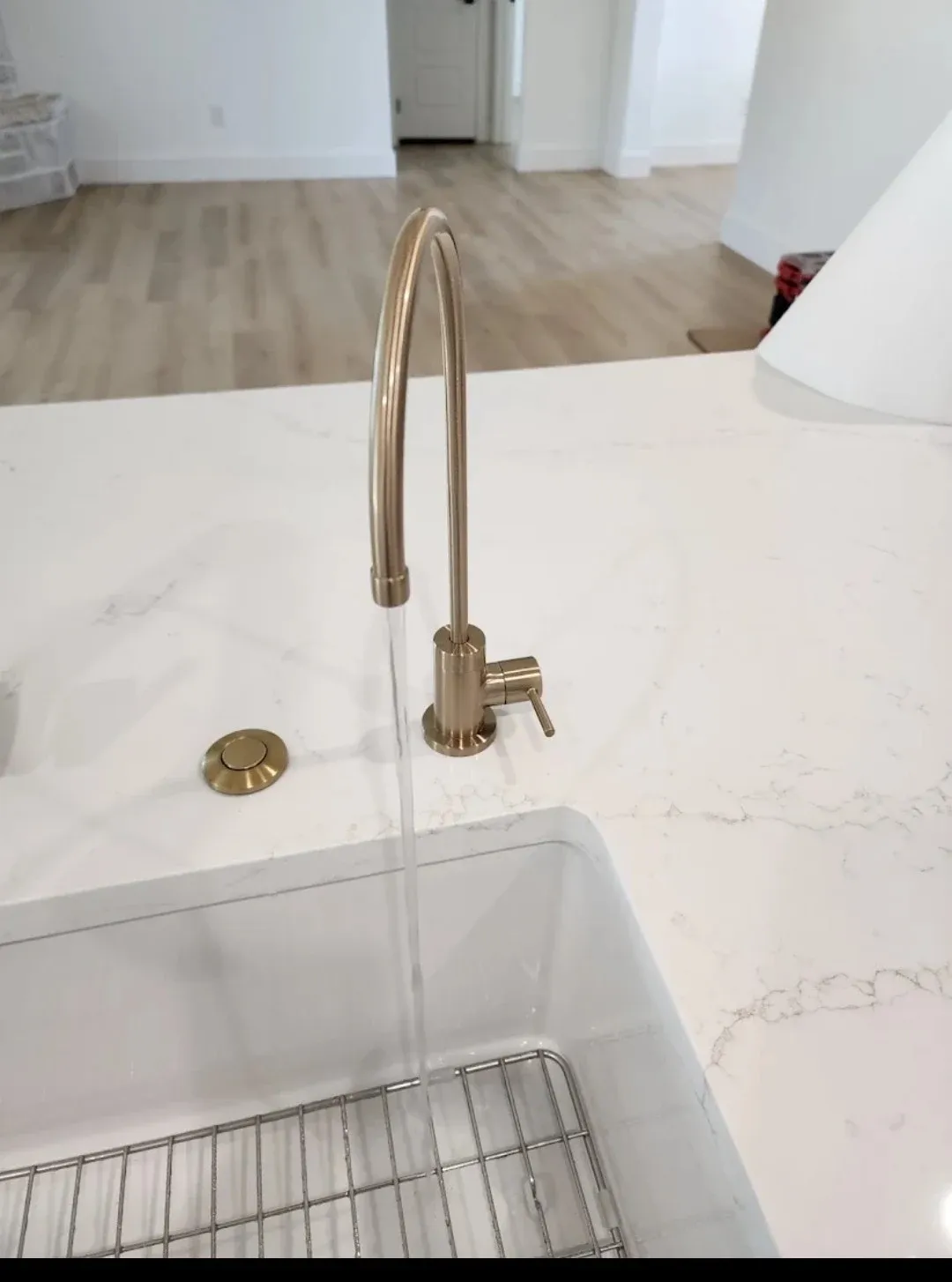 A brushed gold BluePeak reverse osmosis faucet at a kitchen sink, with water running